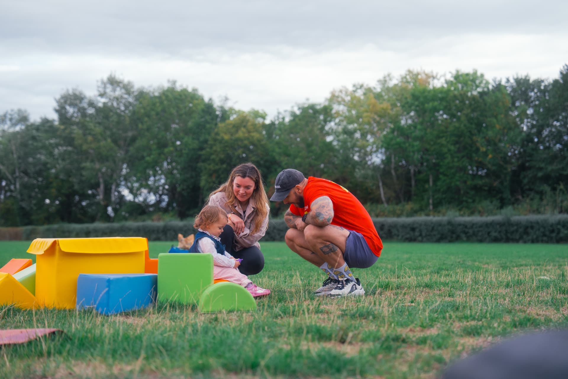 A coach chatting with a parent and toddler beside the soft play area on the field