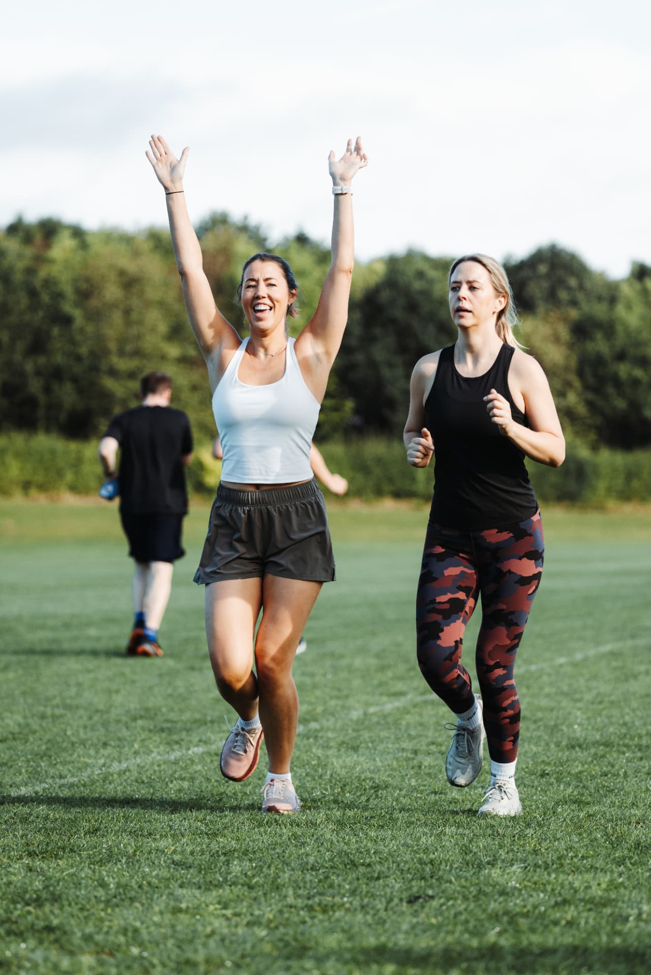 Two members running on the field, one with her arms raised in celebration