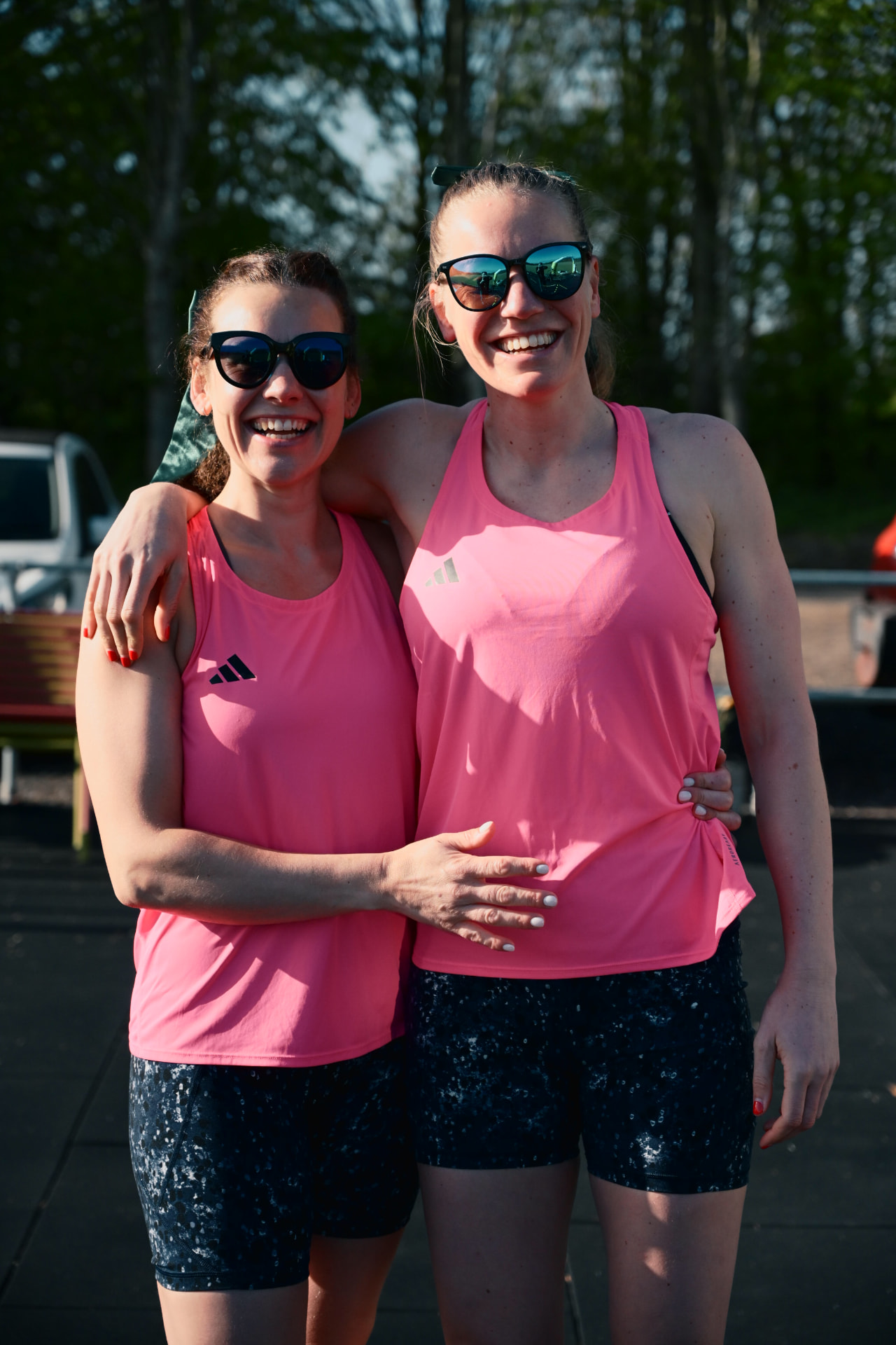 Two members in matching pink vests with their arms around each other, smiling