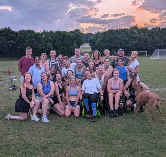 Georgia with a large group of friends and a dog on a playing field at sunset