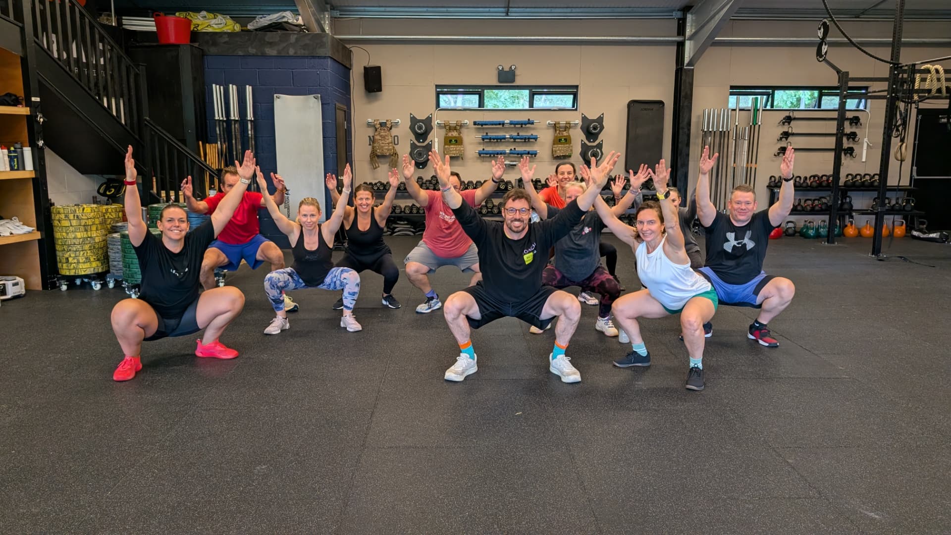 A Beyond Walls class squatting together with their hands raised