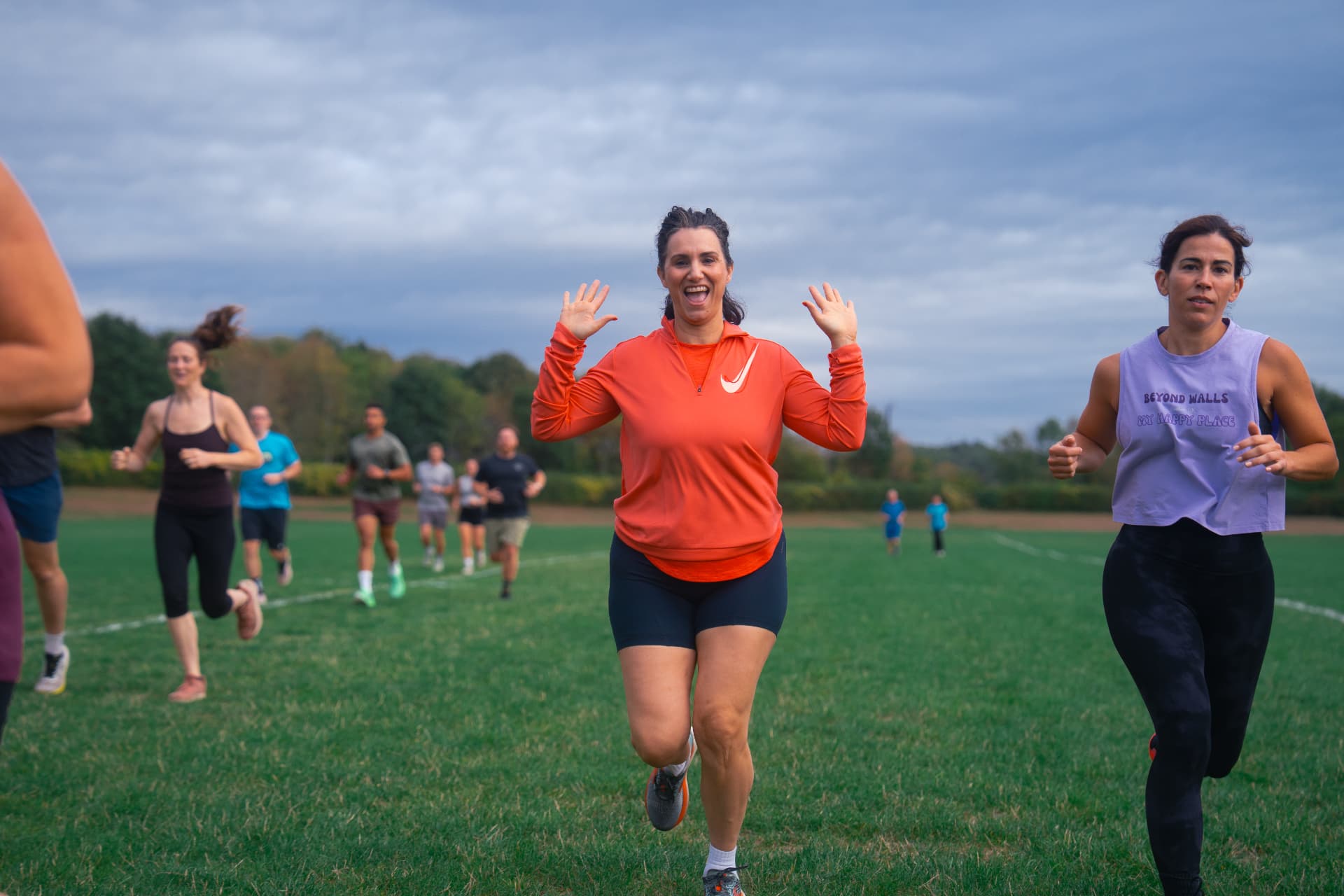 A smiling member waving mid-run on the field