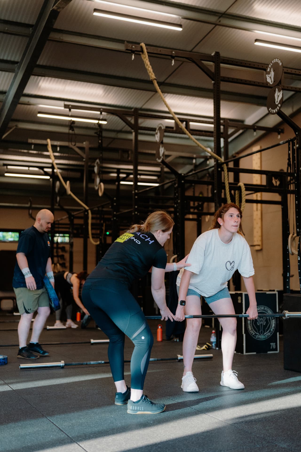 A Beyond Walls coach helping a member with her deadlift technique