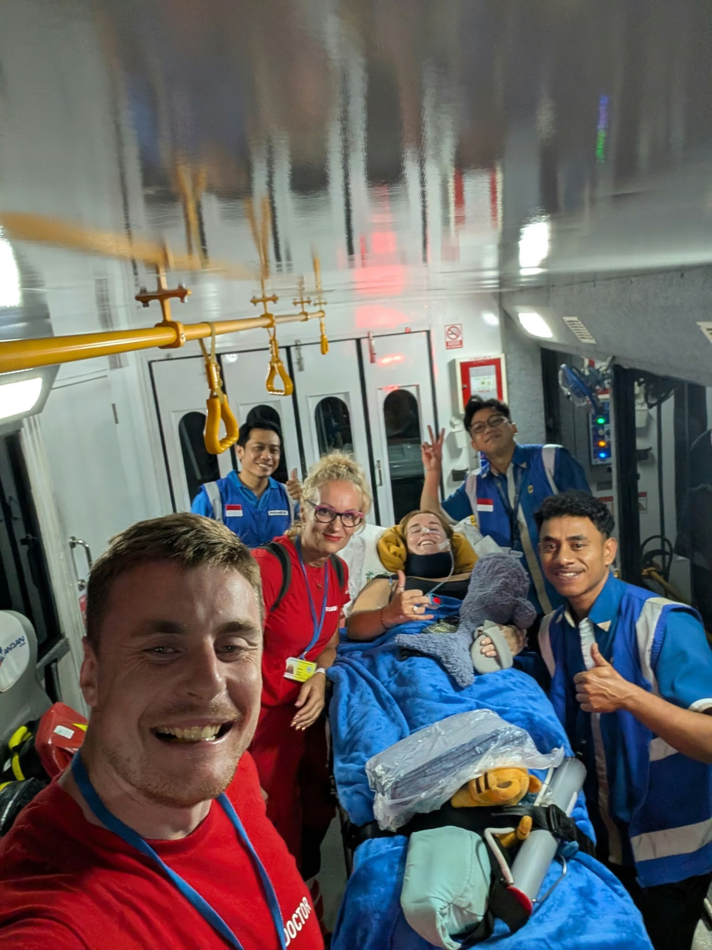 Georgia smiling on a stretcher, surrounded by the medical team supporting her transfer